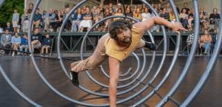 A person inside a large coil doing acrobatics.