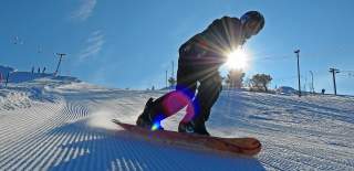 snowboarder i nypløyd bakke med sol og blå himmel i Setesdal