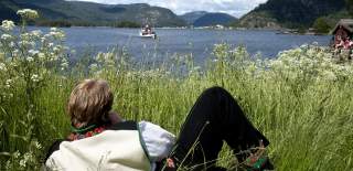 Man lies on grass and enjoys the view towards the steamboat Bjoren, Photo