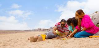 A family playing on the beach making sandcastles