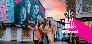 People walking down a street in New Brighton wearing winter clothing with buildings in the background that are covered in street art