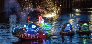 A dragon puppet on the water with fairy lights and