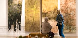 Two women look at an art installation hanging on a wall
