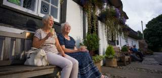 Two ladies enjoy a drink outside a country pub.