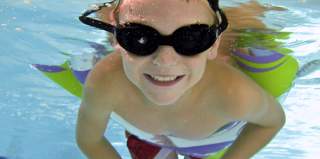 Boy in swimming pool with goggles and a floaty on family getaway in Providence