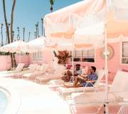 Two guys sitting in lounge chairs at the pink Trixie motel in Palm Springs