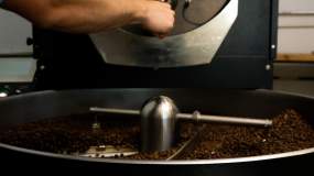 A Honeybee Coffee Co employee works their in-house coffee bean roaster.