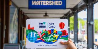 Hand holding a Love Bristol Gift Card shopping voucher outside Watershed, central Bristol - credit Bristol BIDs