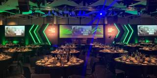 Event setup with round tables and green lights - credit Sounds Commercial