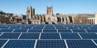 Solar panels on the roof of the We The Curious science centre on Millennium Square on Bristol's Harbourside, with Bristol Cathedral in the background - credit We The Curious