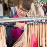 A woman browsing clothes on a rack at a charity shop in Bristol - credit Becky Barnes