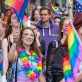 People walking in the Bristol Pride parade wearing rainbow accessories - Credit Paul Box