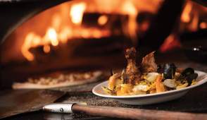 Kaiser Grill Paella dish in front of a pizza oven with fire