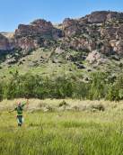 Woman dressed in regalia set against cliffs in field