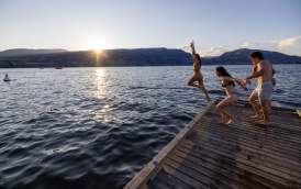 Friends jumping off the dock into Okanagan Lake at sunset in City Park
