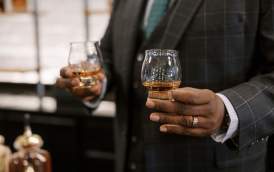 Person holding two glasses with pours of bourbon