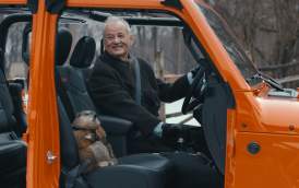 Bill Murray sitting in an orange jeep with groundhog in passenger side.