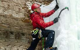 Aaron Mulkey climbing a wall with ice axes