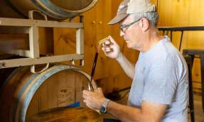Mike Fritze draws a sample of red wine directly from an oak barrel at a Carraige House Wineworks in Loudoun.