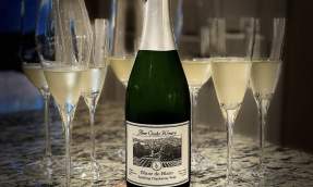 Three Creeks Winery Blanc de Blanc sparkling Chardonnay bottle surrounded by filled flutes on a granite counter