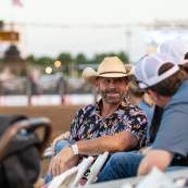 A fan in the crowd talking to a friend enjoying the Rodeo.