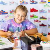 Image of child painting various shoe drawings for a piece featured at the 2025 Spring Art Stomp