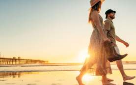 Couple walking Oceanside beach with cowboy boots