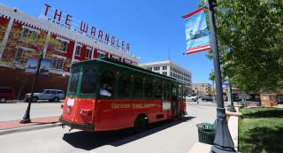 Red and green trolley passing through historic streets during a Cheyenne Trolley Tour in Laramie County, Wyoming.