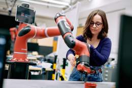 Young woman working with a robotic arm