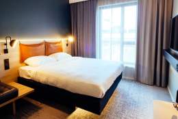 A pristine room in a hotel, a floating bed in the centre, from under which light spills out.