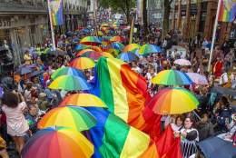 Birdseye view of the crowd carrying rainbow umbrellas and a giant rainbow flag at Birmingham Pride Festival