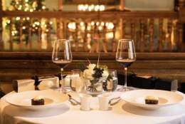 festive table with two plates, wine glasses and christmas crackers