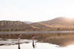 Two paddleboarders on Kamloops Lake surrounded by the natural beauty of the BC mountains in the background.