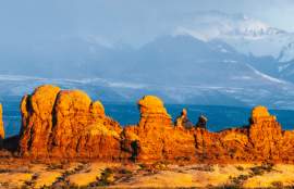 The red rocks of Turret Arch and the surrounding rock fins in The Windows Section of Arches National Park, framed against the snow-capped La Sal Mountains in Moab, Utah.