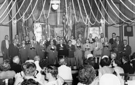 Historic black and white photo of a mens chorus performing at Saengerrunde Hall