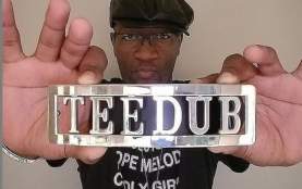Tee Double holds silver sign saying TEE DUB towards camera