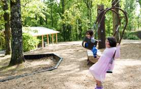 Two children swing on a double swing at Dunnavant Valley Park on a beautiful summer day.