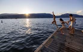 Friends jumping off the dock into Okanagan Lake at sunset in City Park