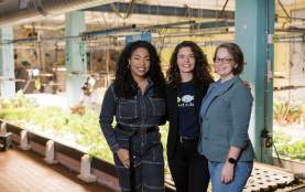 Three women smiling at camera with indoor garden in the background