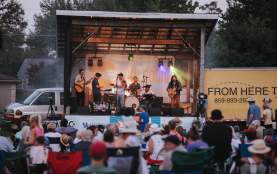 Stage with band performing in front of audience in lawn chairs