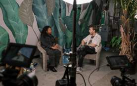 Two people sitting in chairs facing each other during video interview, shows camera/behind the scenes