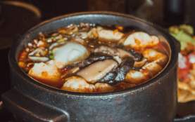 Hot pot with lots of plates of food around it.