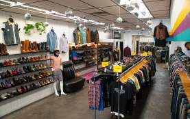 Interior of a vintage clothing store featuring racks of colourful secondhand clothing, shelves of shoes and boots, mannequins, and hanging disco balls.