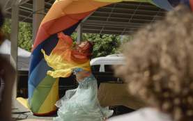 In a flowy dress, a women dances under a rainbow.
