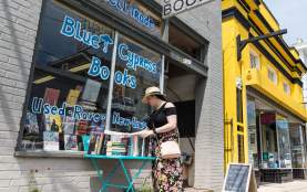 a woman browses the selection of books outside of Blue Cypress Books on Oak Street