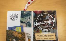 A Oxford Handcrafted Trail zine with cutouts, stickers, and stamps added