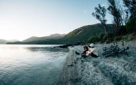 Bike riders sitting by lake at dusk