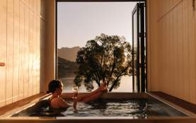 Woman relaxing with a glass of win in a hot tub at Driftaway, Queenstown