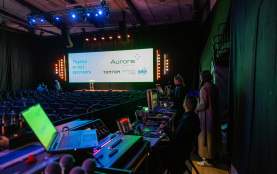 Behind the scenes of an event tech setup with large screens, lights and computer controls