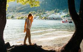 Family walking along the lake at Queenstown Bay in summer